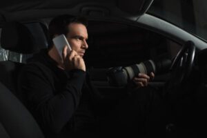 Investigadores privados; investigador hablando por teléfono en un auto